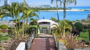 A pathway leading to a gated entrance with a view of a beach and ocean.
