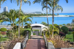 A pathway leading to a gated entrance with a view of a beach and ocean.