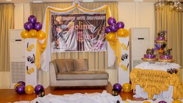 A room with a sofa, a table with a cake, and balloons.
