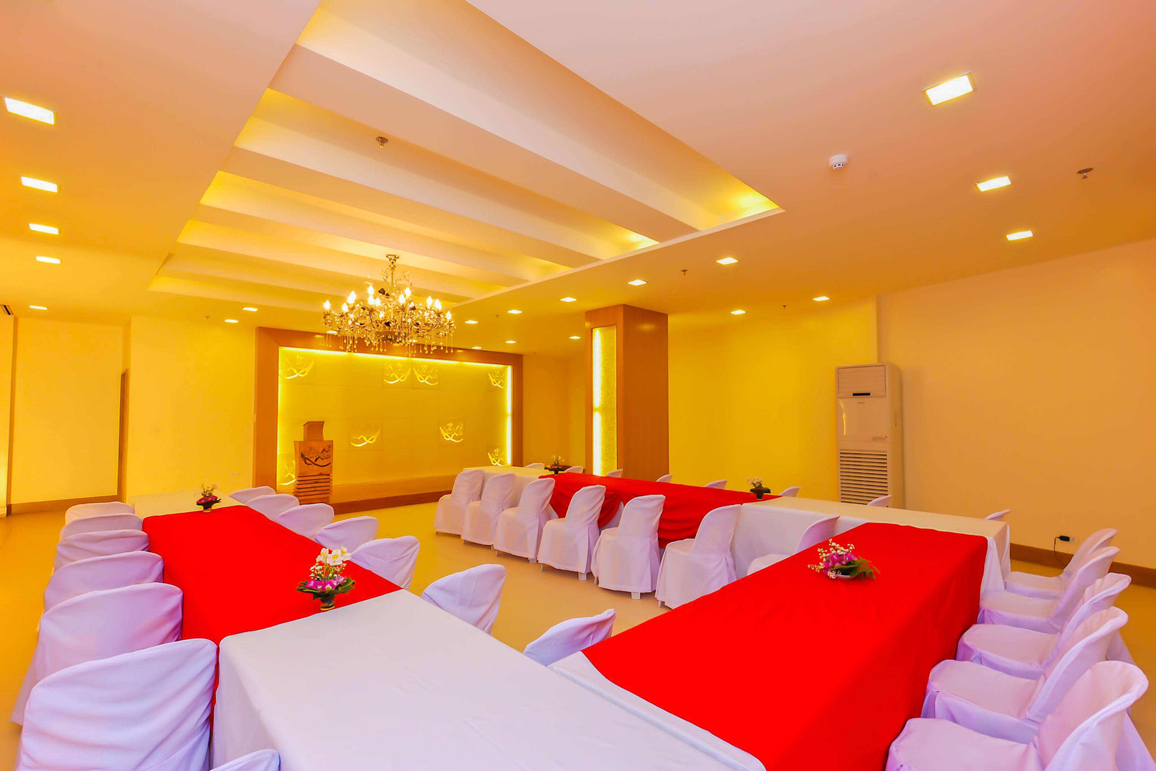 A conference room with tables and chairs, a chandelier, and a red carpet.