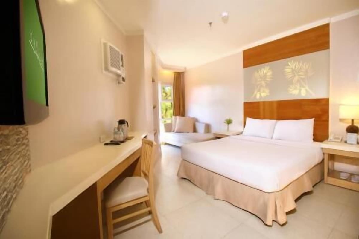 A hotel room with a bed, a desk, a chair, a nightstand, and a wall-mounted TV.