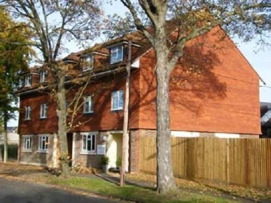 A two-story brick house with a sloped roof, a wooden fence, and a driveway.