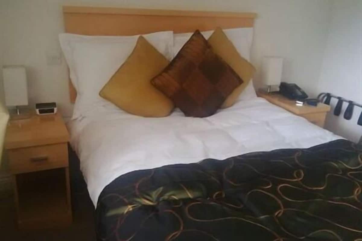 A hotel room with a bed, a nightstand, a lamp, and a telephone.