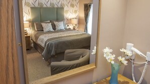 A bedroom with a bed, bedside tables, a mirror, a vase with flowers, and a telephone. - The Commercial Hotel (Aboyne)