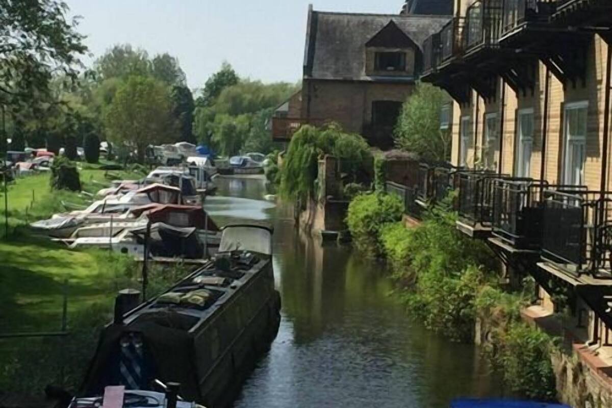 Un canal avec des bateaux, un immeuble doté de balcons et de la verdure.