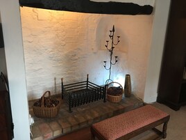 A fireplace with a metal stand, a bench, and two baskets on the mantel.