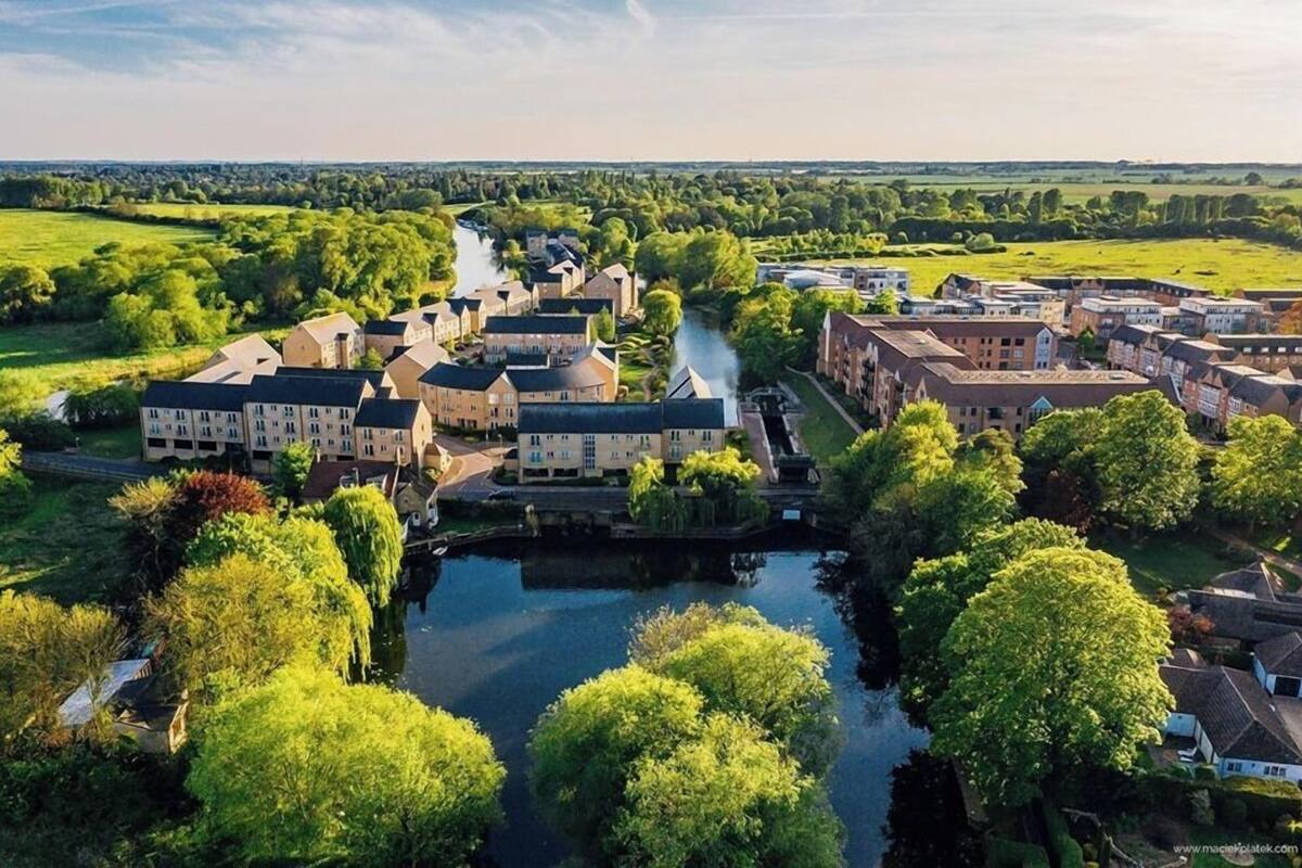 Une vue aérienne d’une ville historique traversée par une rivière, entourée d’une végétation luxuriante et dotée d’une architecture traditionnelle.
