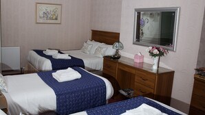 Ein Hotelzimmer mit zwei Betten, einem hölzernen Schminktisch, einem Spiegel und einer Heizung.