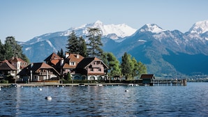 Une propriété au bord du lac, avec des bâtiments de style chalet, un quai et des montagnes en arrière-plan.