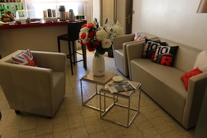 A living room with a sofa, armchairs, a coffee table, and a vase with flowers. - The Originals City, Hôtel Dau Ly (Bron)