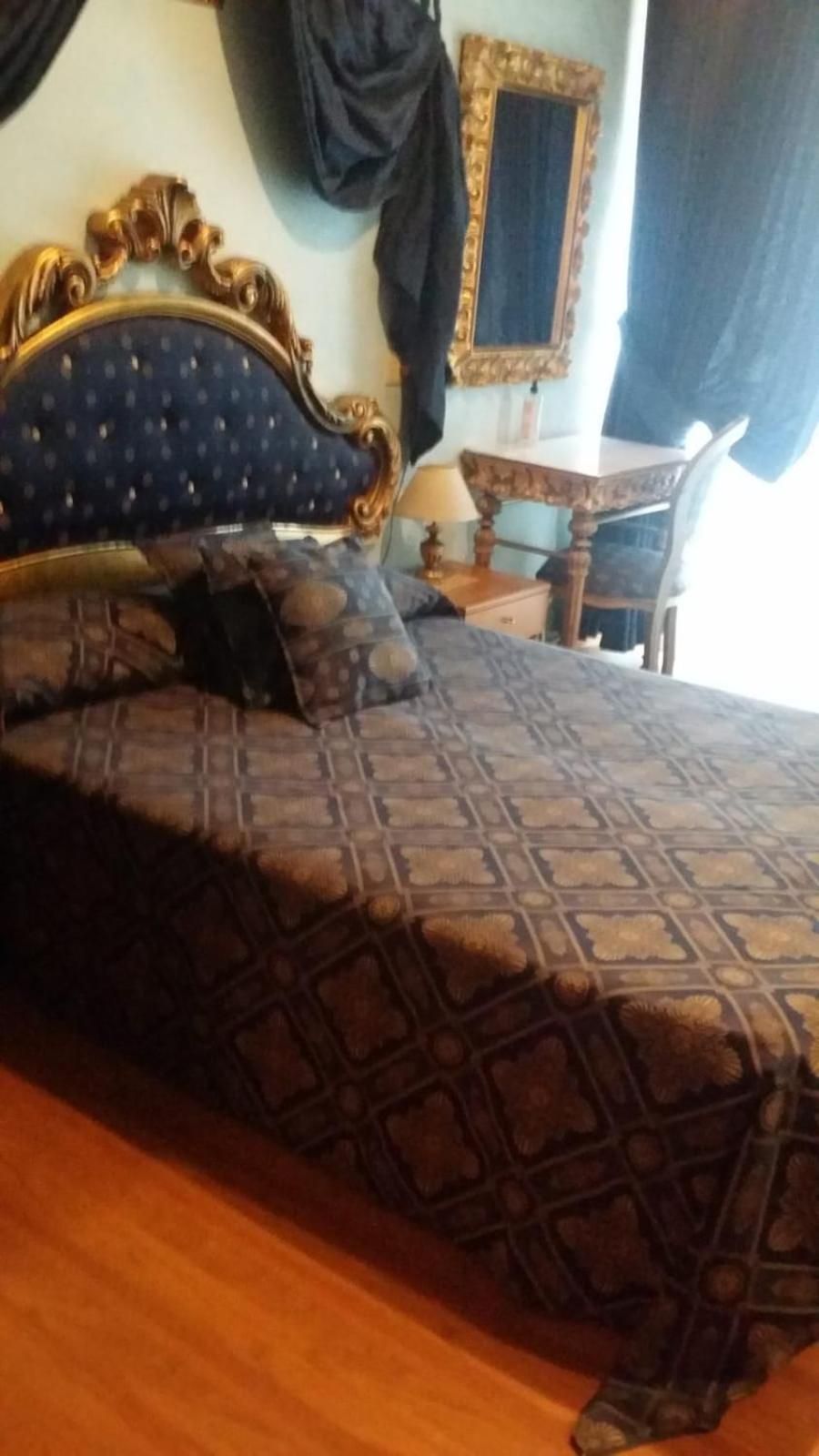 Un lit avec une couvre-lit à motifs, une tête de lit en bois et une table de chevet avec une lampe.