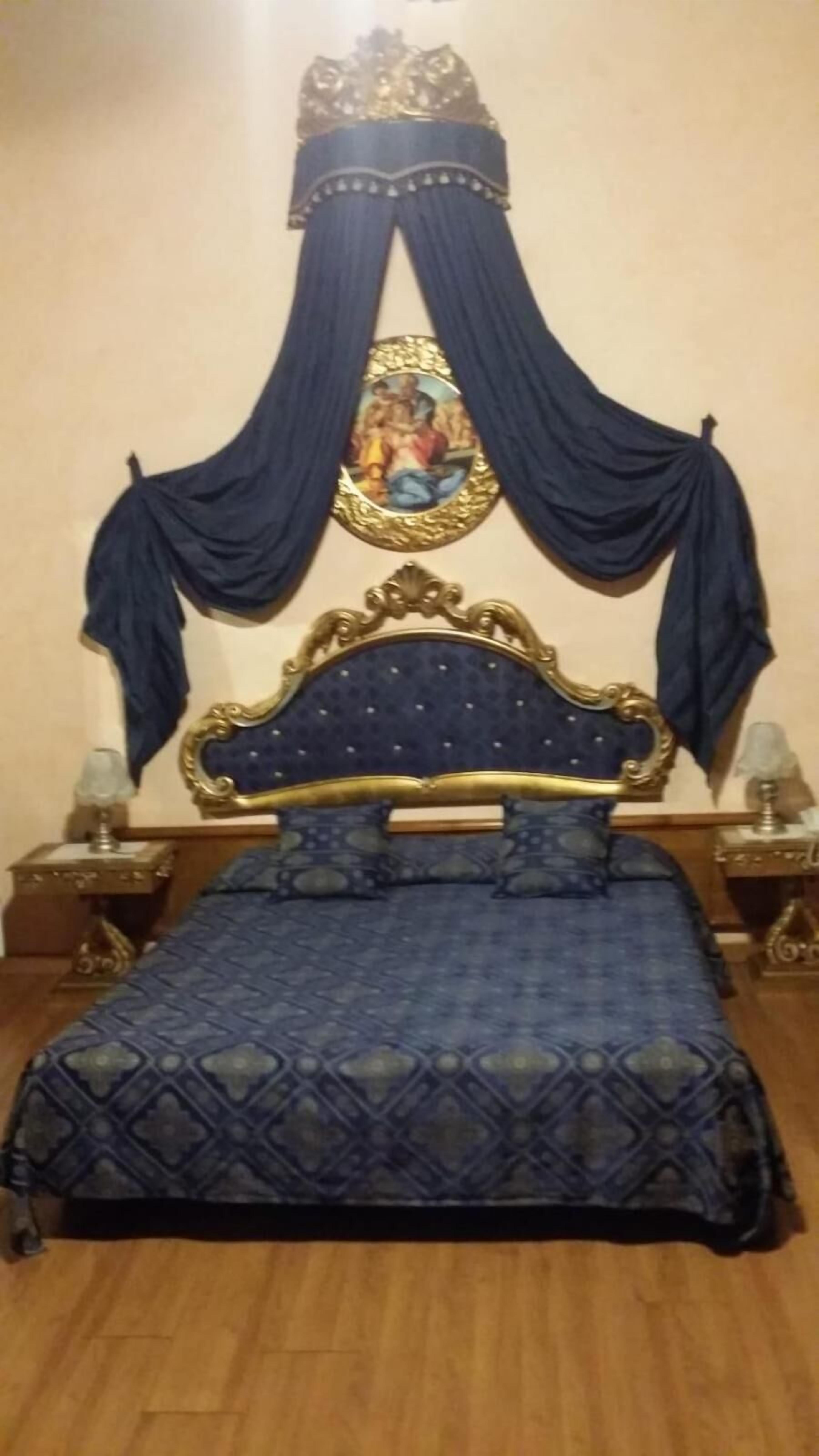 A bedroom with a bed, a nightstand, a lamp, and a wall-mounted picture.