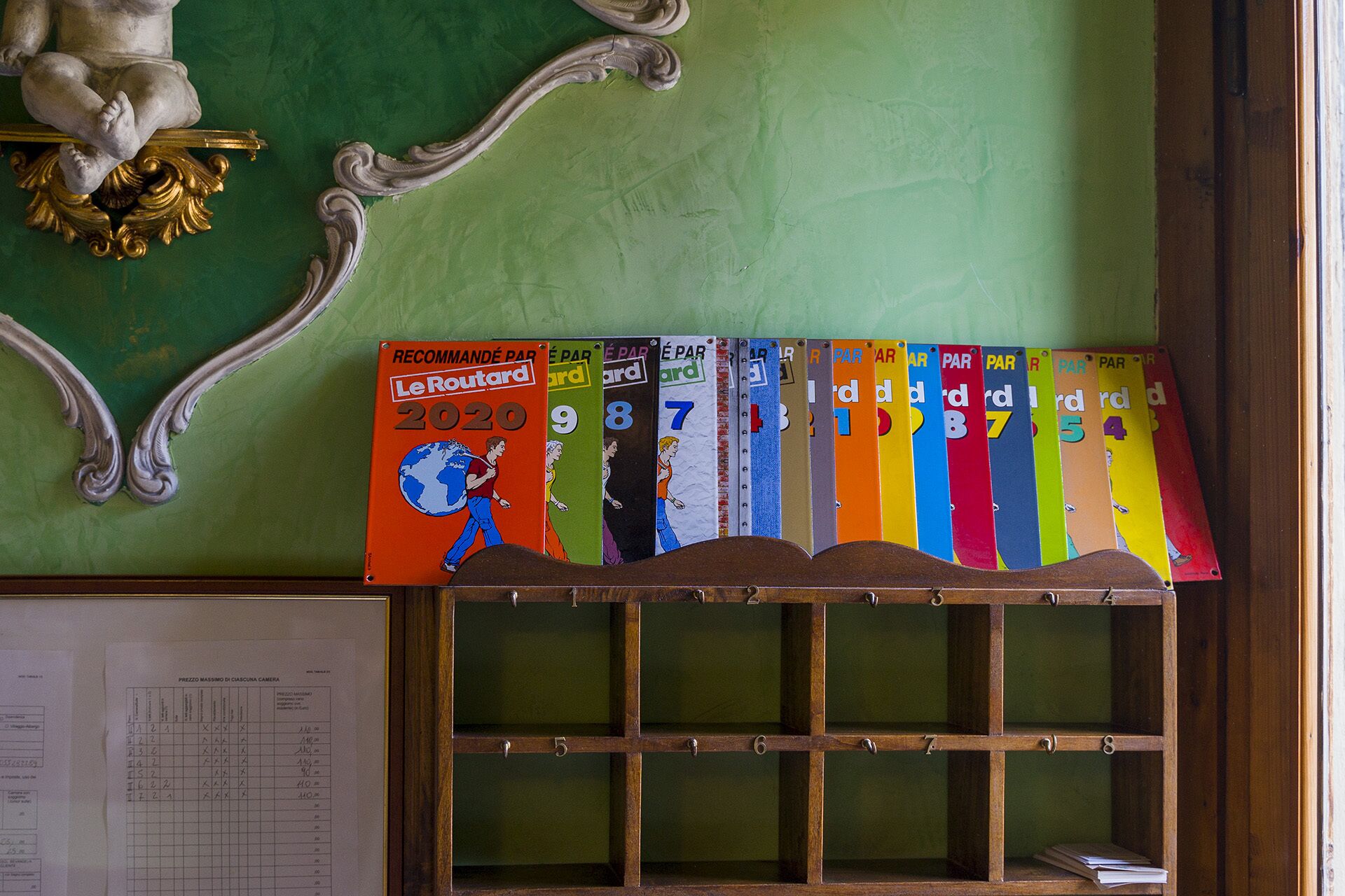 Une rangée de livres aux couvertures colorées, alignés sur une étagère, chaque livre étant identifié par un numéro.