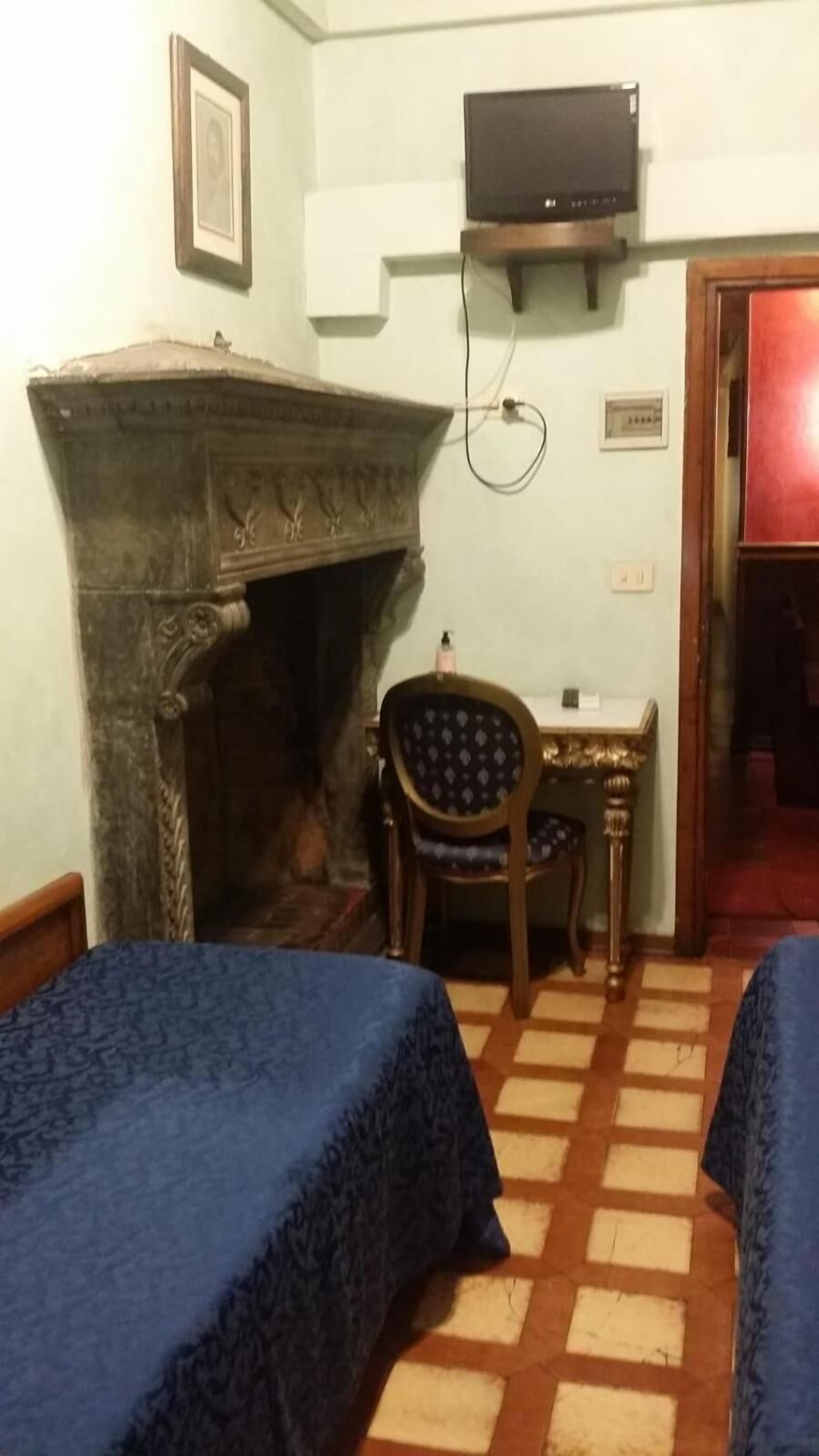 Een kamer met twee bedden, een open haard, een televisie en een stoel.