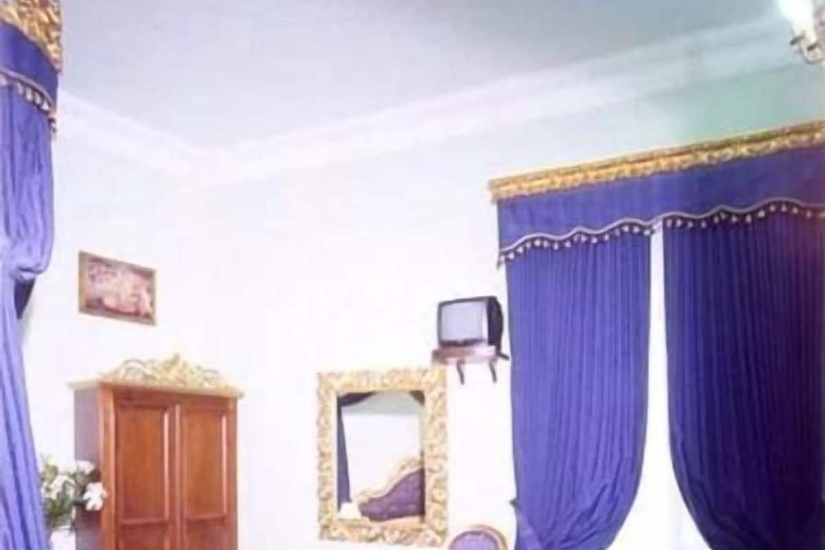 A bedroom with a bed, a chair, a television, and a cabinet.