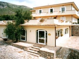 Un edificio a due piani con facciata in pietra, diversi balconi con piante in vaso e una scala in pietra che conduce all'ingresso.