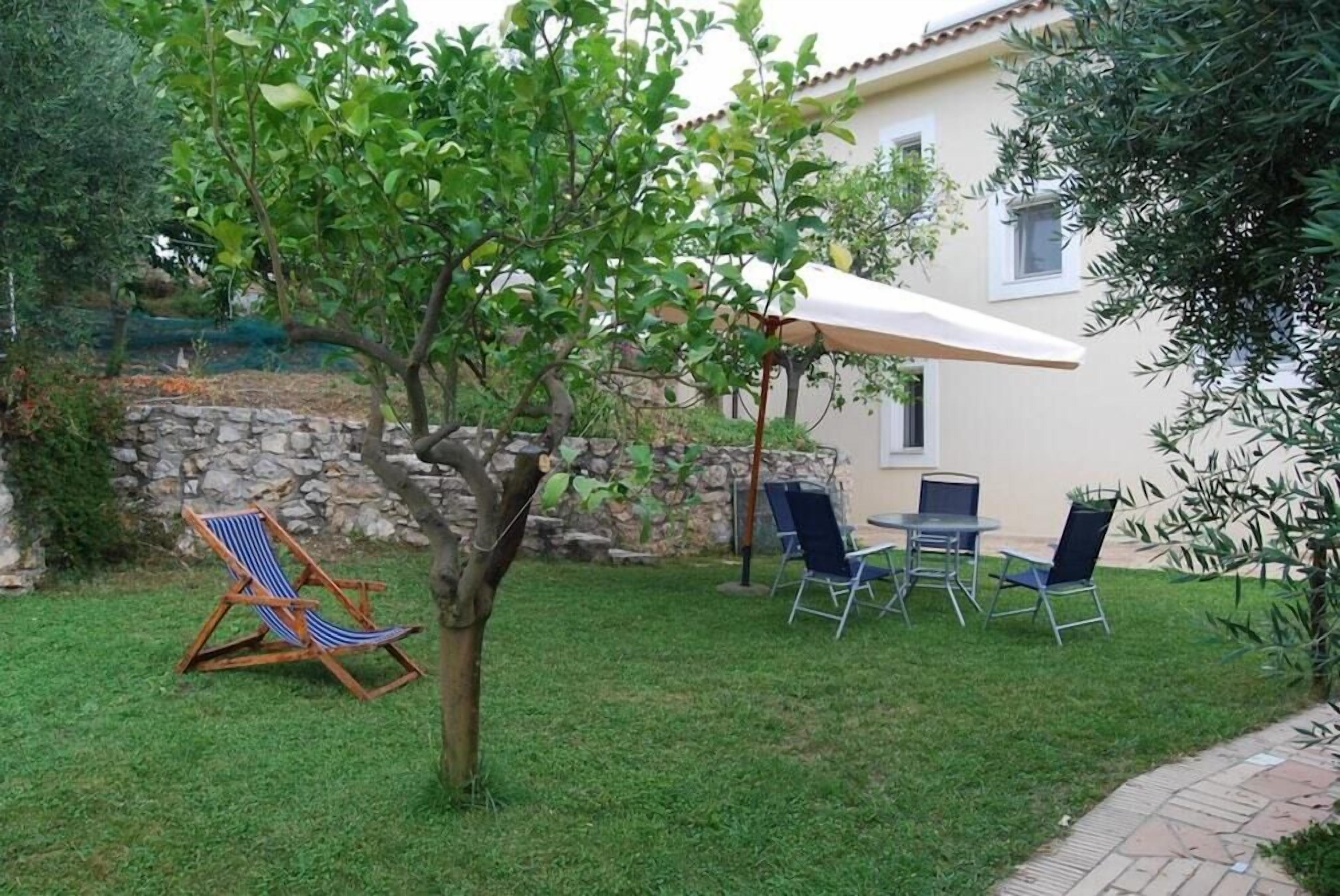 Un patio con una mesa, sillas, un árbol y un muro de piedra.