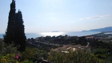 Un borgo costiero con vista sul mare, edifici dall'architettura mediterranea e un cipresso ben visibile.