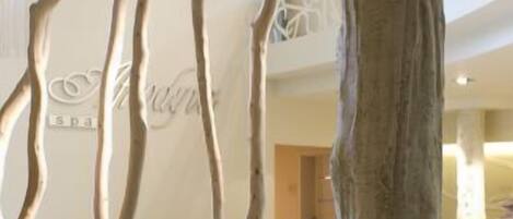 Un interno moderno con una struttura a forma di albero sullo sfondo, un divano in lontananza e un'ampia stanza con soffitto alto.