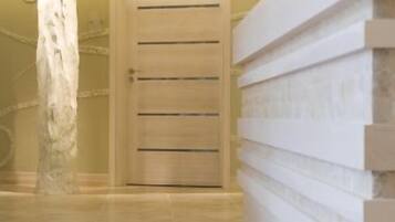 A hallway with a wooden door and a white wall with horizontal lines.