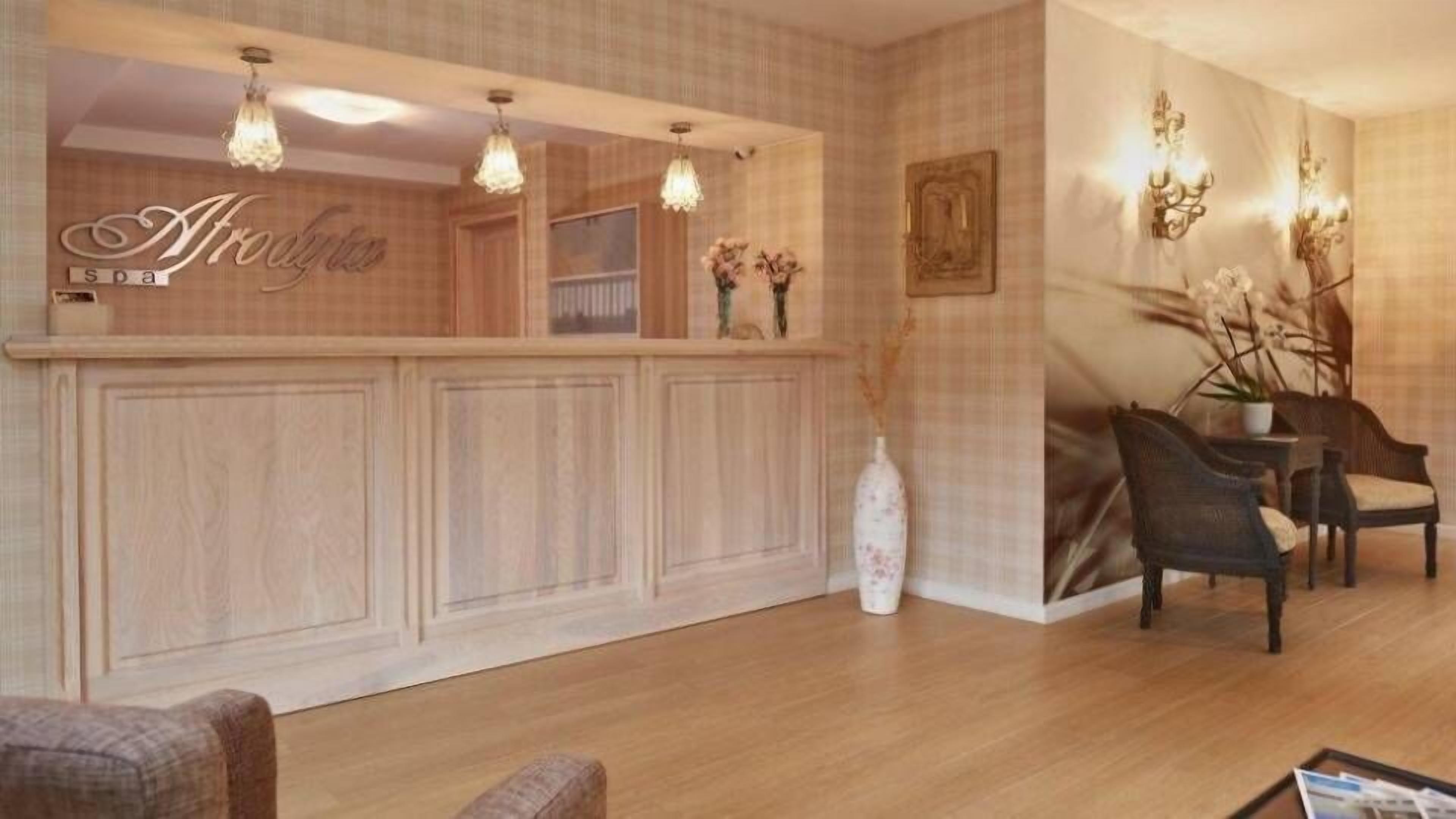 A reception area with a wooden reception desk, pendant lighting, and a seating area with chairs and a table.