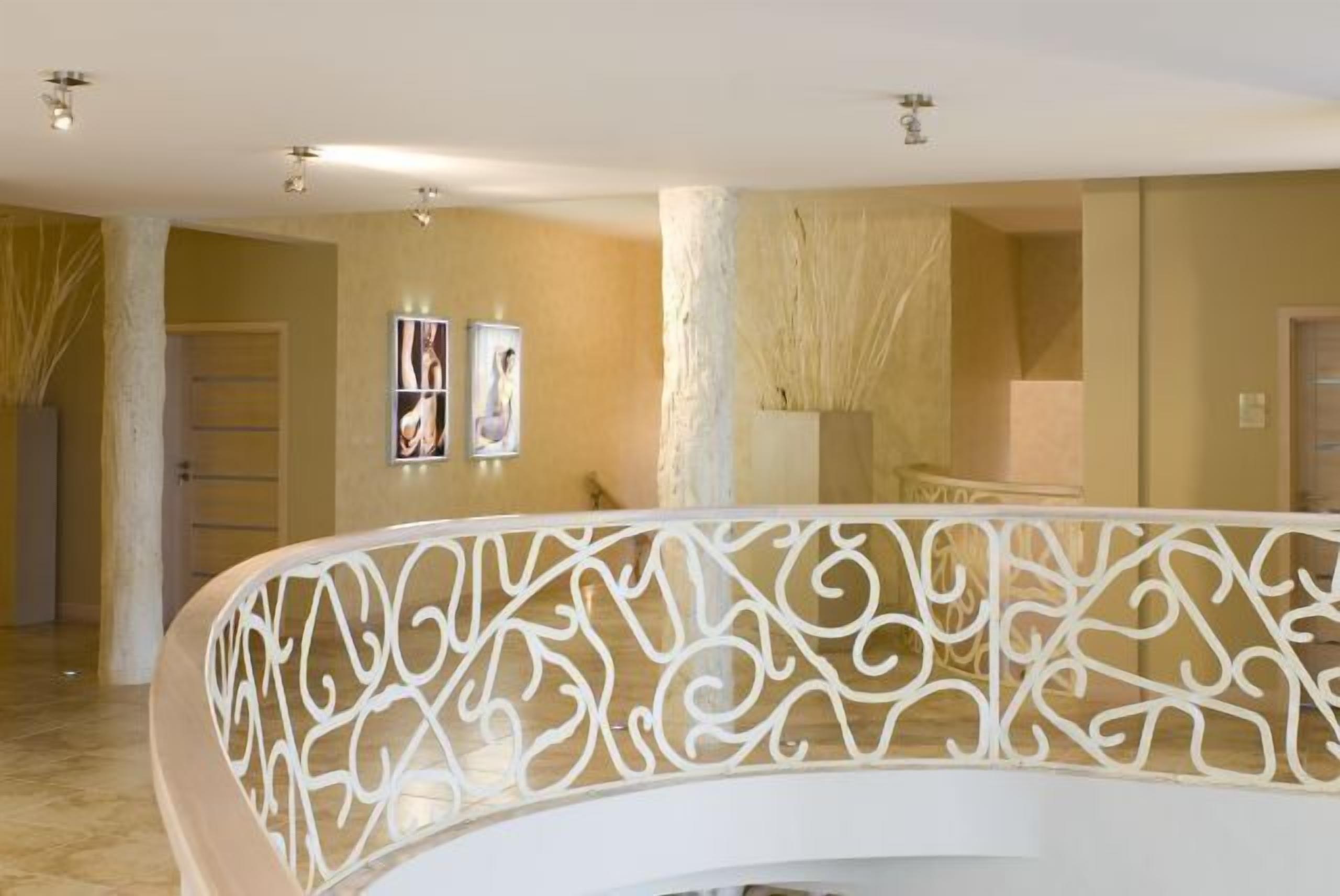 Um hall espaçoso com um elegante guarda-corpo branco, uma coluna imponente e obras de arte nas paredes.