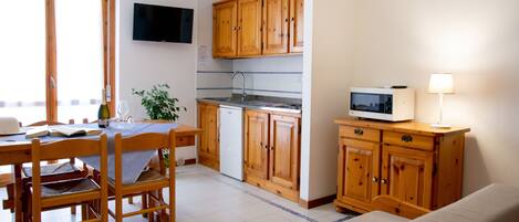A kitchen with wooden cabinets, a microwave, and a dining area with chairs and a table.