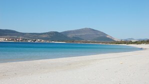 Una platja amb aigua turquesa cristal·lina, sorra daurada i muntanyes al fons.