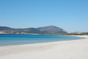 Una playa cerca, arena blanca, sombrillas, toallas de playa