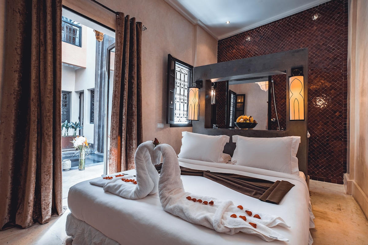 Habitació d'hotel amb un llit gran, vistes a la ciutat i un balcó amb cortines.