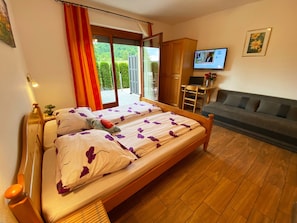 Une chambre avec un lit, un canapé, une télévision et une vue sur la verdure.