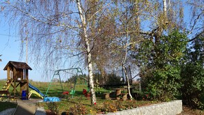 Une aire de jeux avec un toboggan, des balançoires et une cabane en bois.