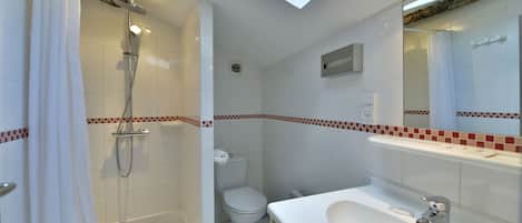Un baño moderno con tragaluz, ducha, inodoro y lavamanos.
