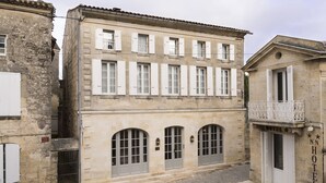 A historic building with a stone facade, multiple windows with shutters, and a balcony with a wrought iron railing. - Auberge de la Commanderie (Saint-Émilion)