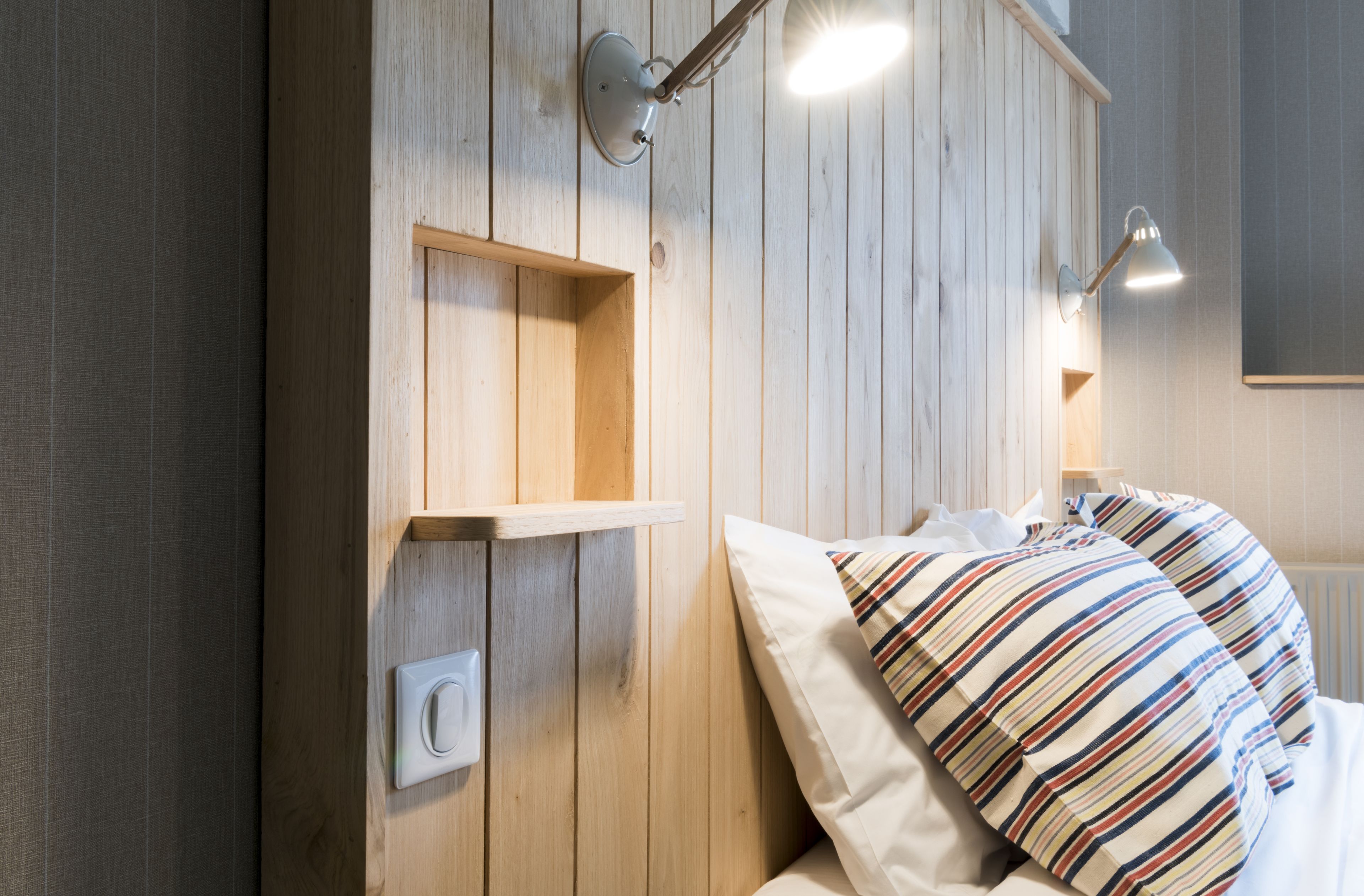 Cabecera de madera con estantes integrados y lámparas de noche.