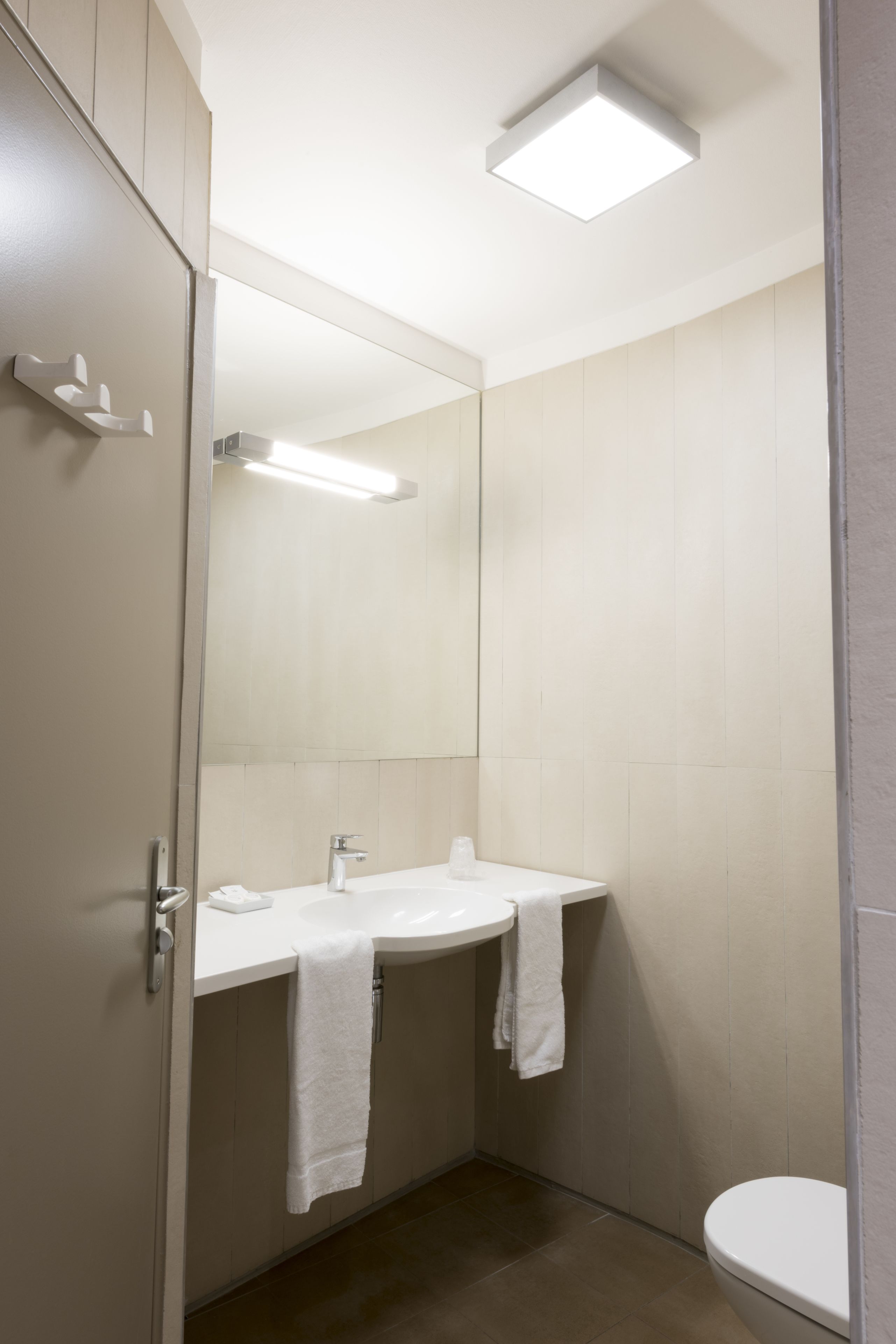 A modern bathroom with a white sink, mirror, and toilet.