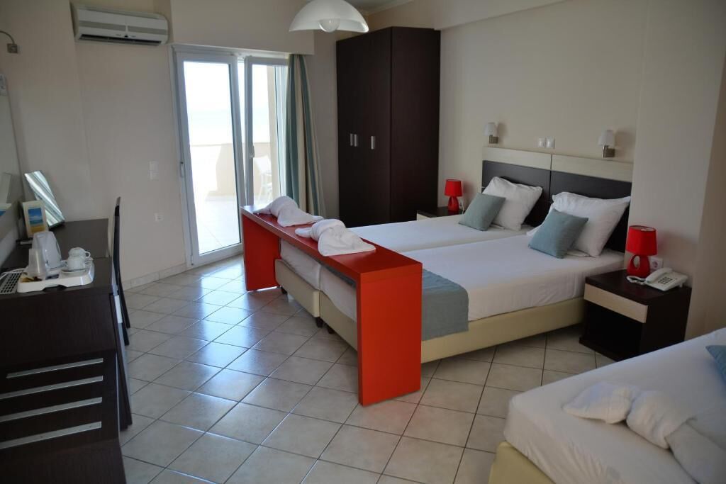 A hotel room with two beds, a desk, a wardrobe, and a balcony.