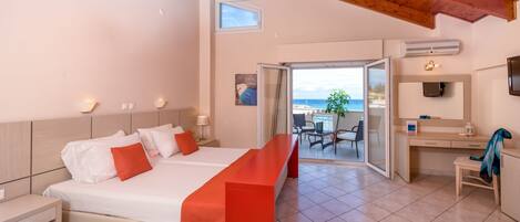 A modern hotel room with a large bed, a desk, and a balcony with a view of the sea.