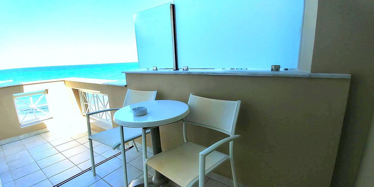 Un balcón con mesa y sillas, con vista al mar.