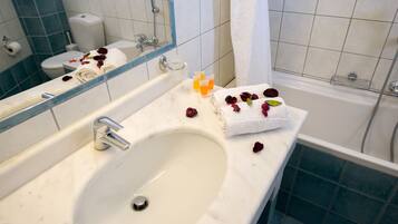 A bathroom with a white sink, a mirror, a toilet, and a bathtub.