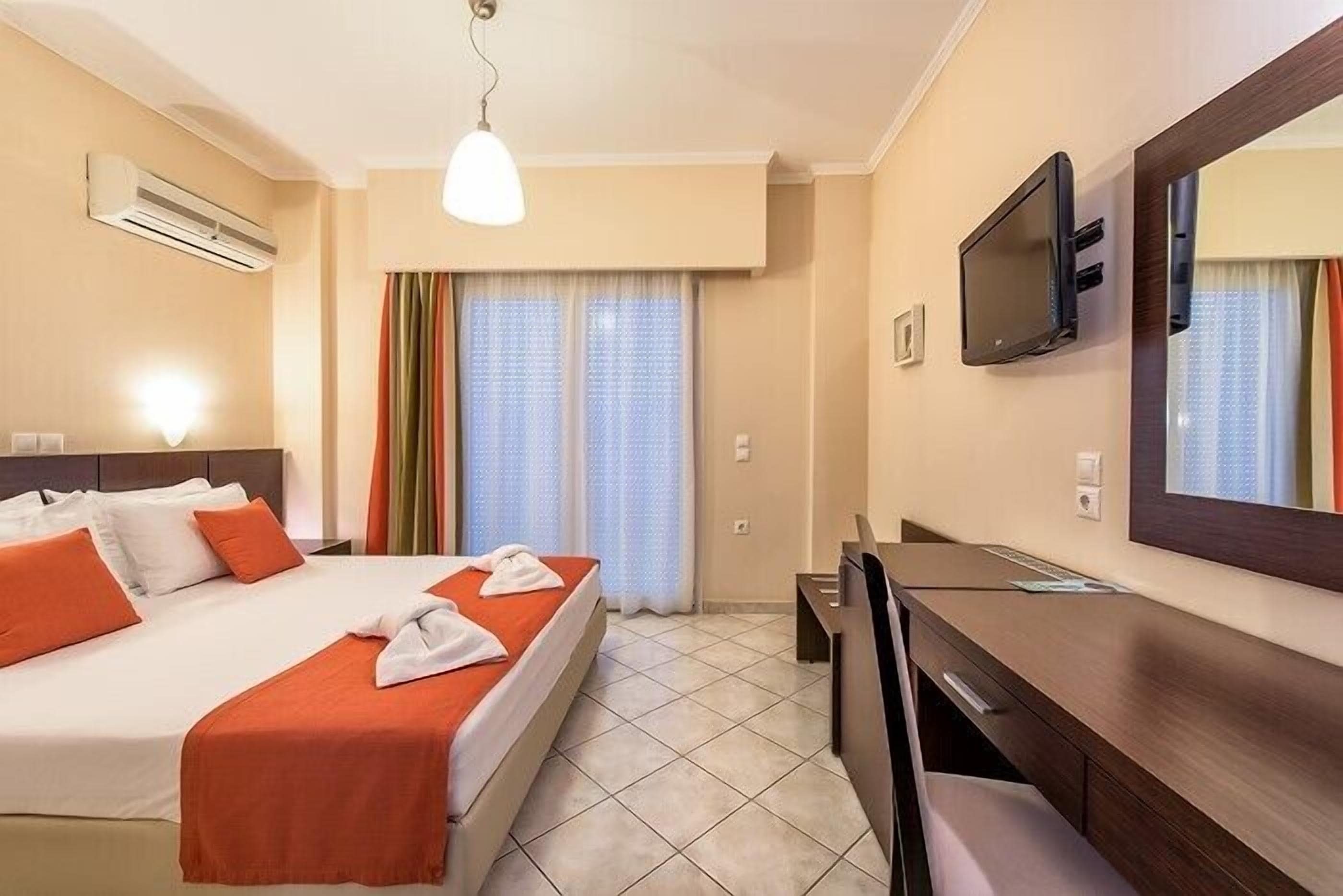 Una camera d'albergo con un letto, una scrivania, un televisore e un condizionatore d'aria.