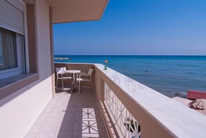 Un balcone con vista sul mare, un tavolino e due sedie.