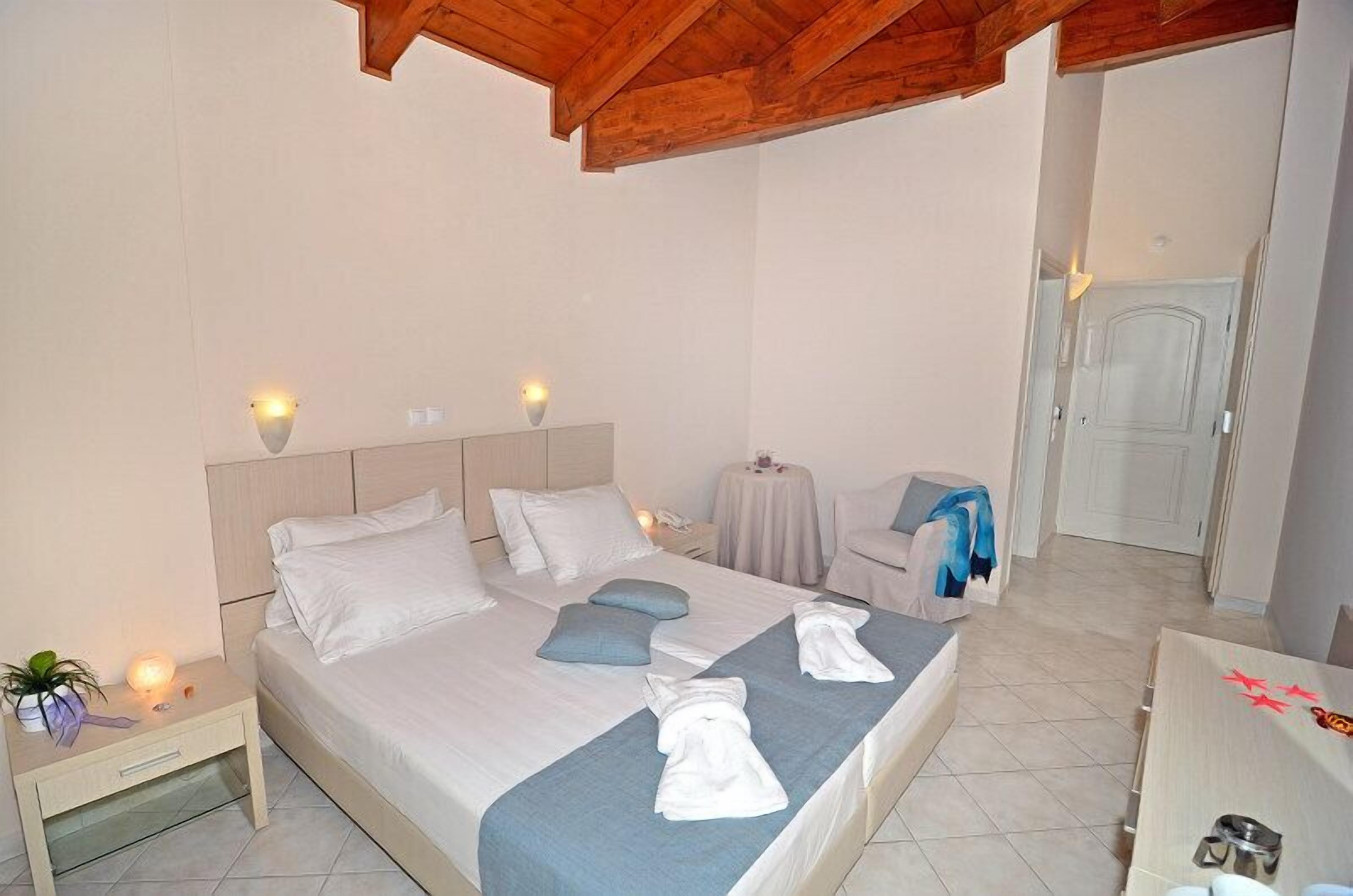 A bedroom with a bed, bedside tables, a small table, and a chair.