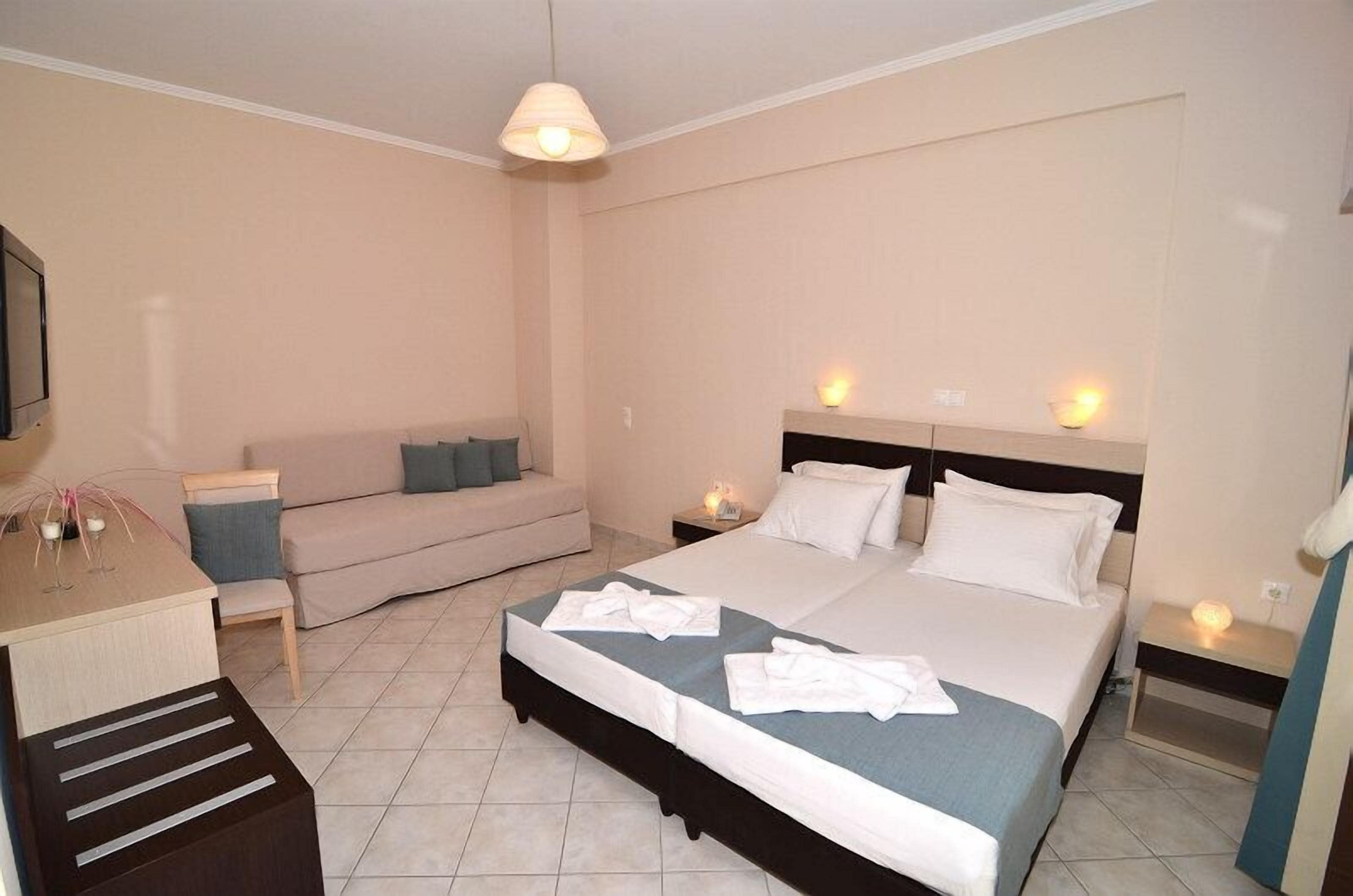A hotel room with a bed, bedside tables, a desk, and a sofa.