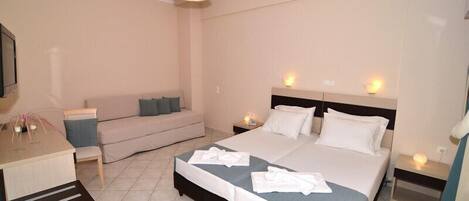 A hotel room with a bed, bedside tables, a desk, and a sofa.