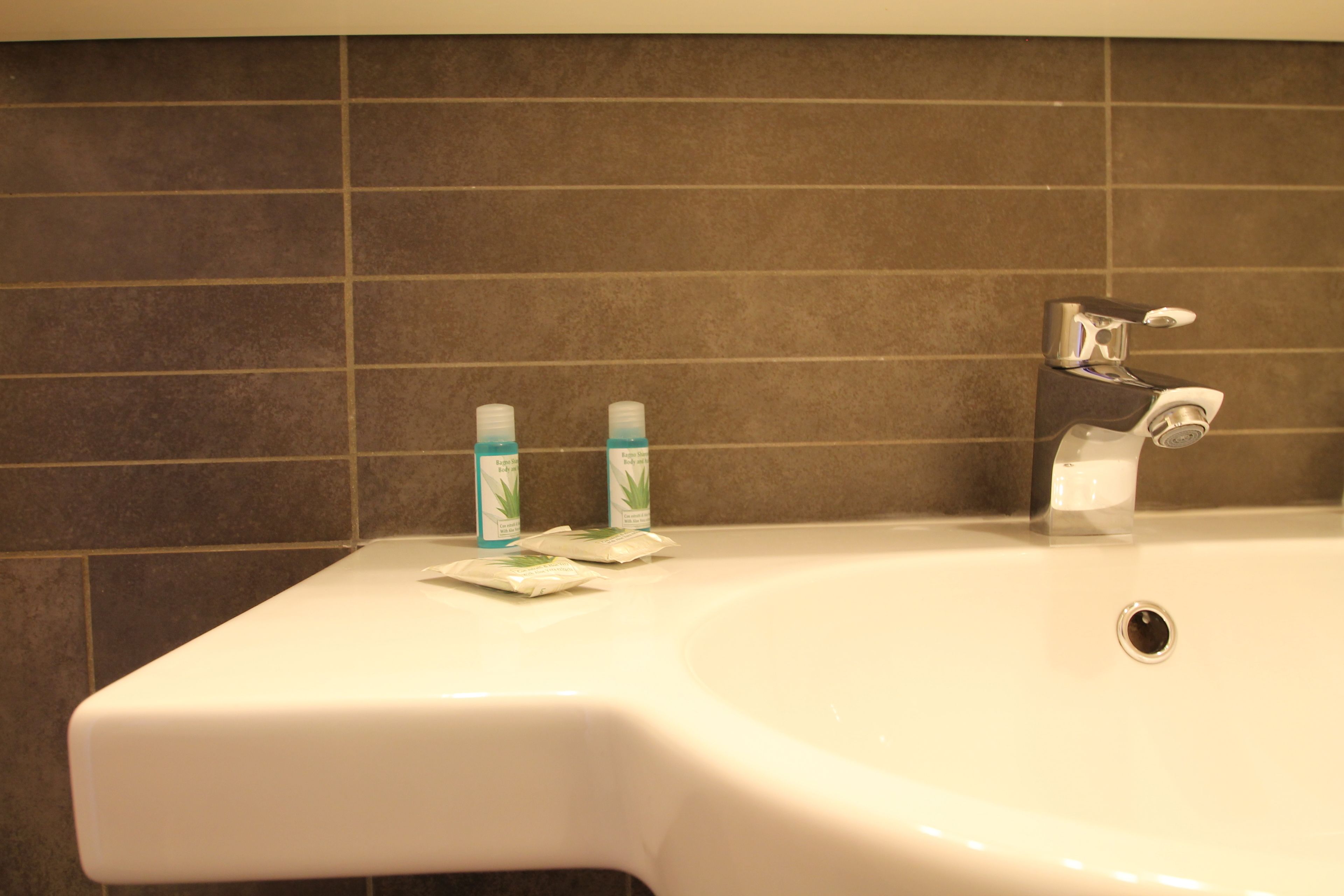 A bathroom sink with two toothbrushes and a soap dispenser.