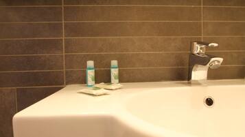 A bathroom sink with two toothbrushes and a soap dispenser.