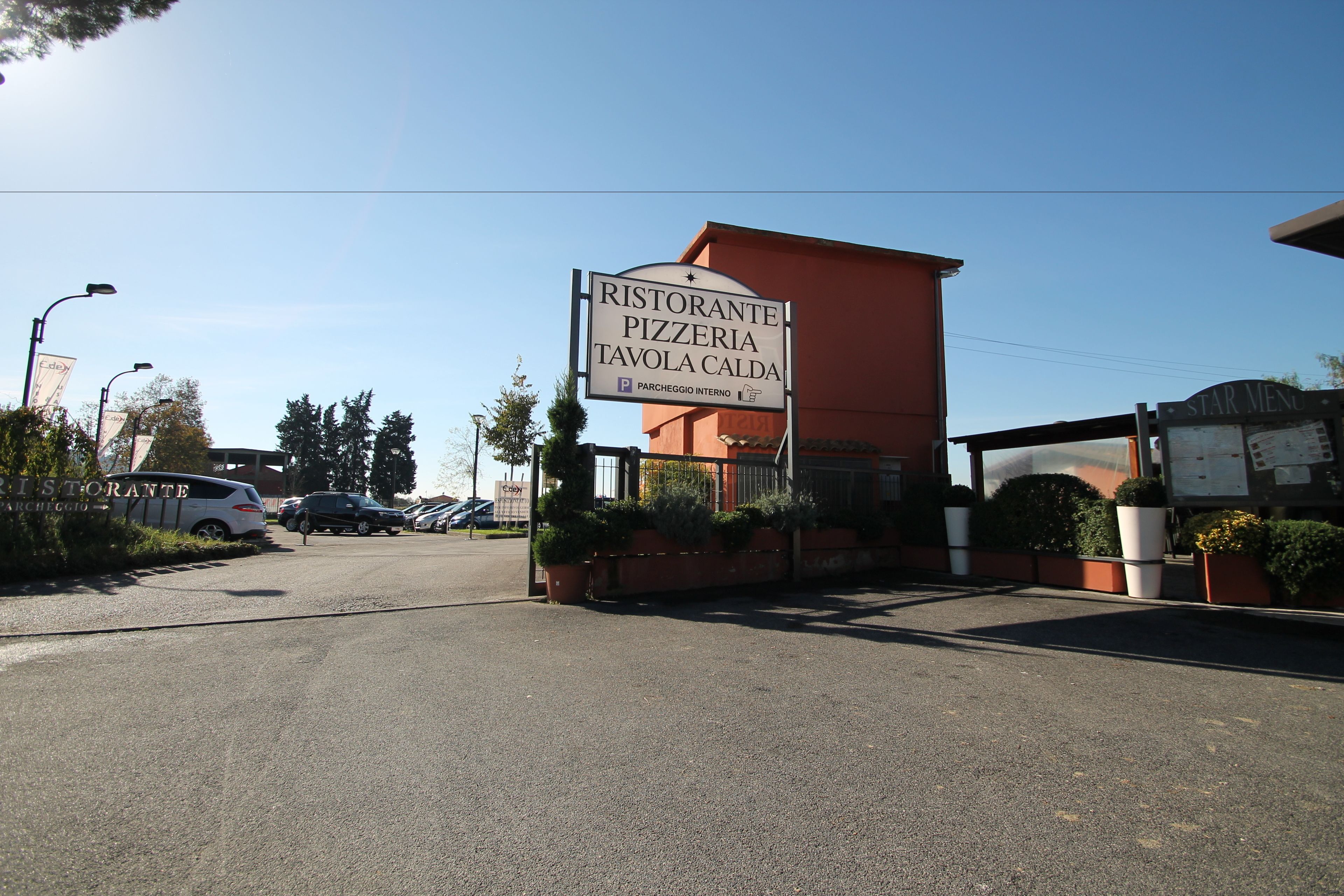 Une enseigne indiquant un restaurant et une pizzeria, avec un espace de stationnement devant.