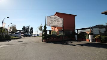 Une enseigne indiquant un restaurant et une pizzeria, avec un espace de stationnement devant.