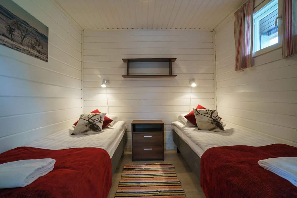 A room with two beds, a small table, and a window with curtains.